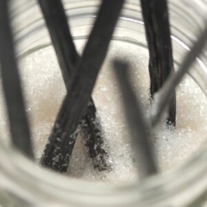 Grade A vanilla beans (pods) styled on a clean white background in warm earth tones